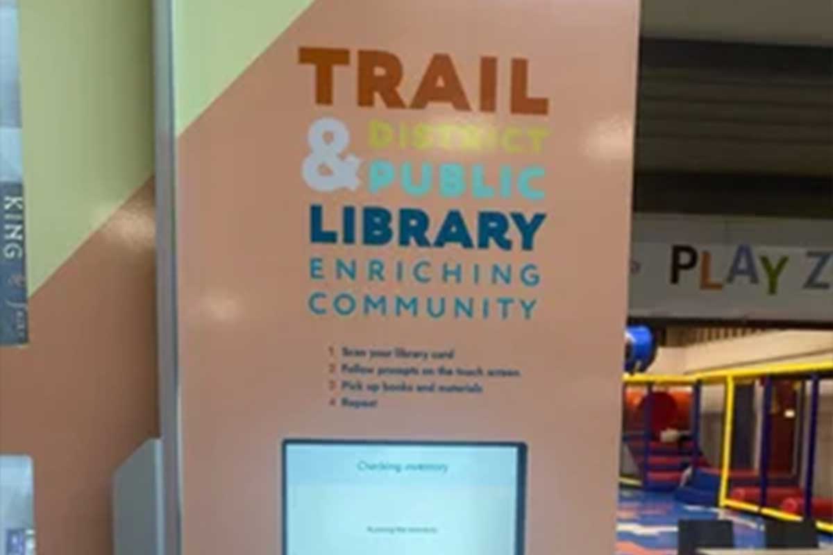 Mini Library Trail & District Public Library kiosk with instructions and a touchscreen in a colorful indoor play area.
