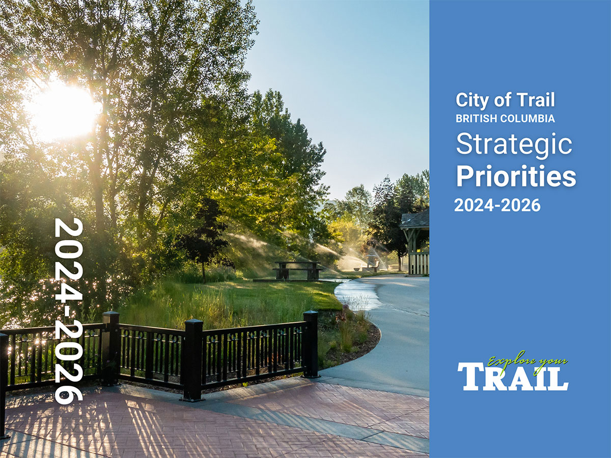 Sun shining through trees over a park pathway with sprinklers watering grass, text about City of Trail strategic priorities