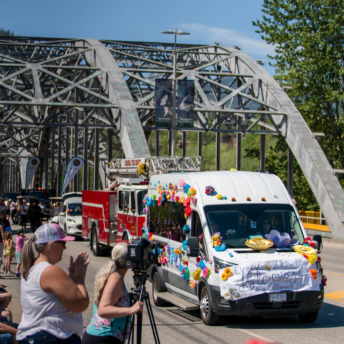 SCD Gallery_01 Van decorated with colorful flowers and a banner reading "Every flower blooms at a different pace" in a parade by a steel