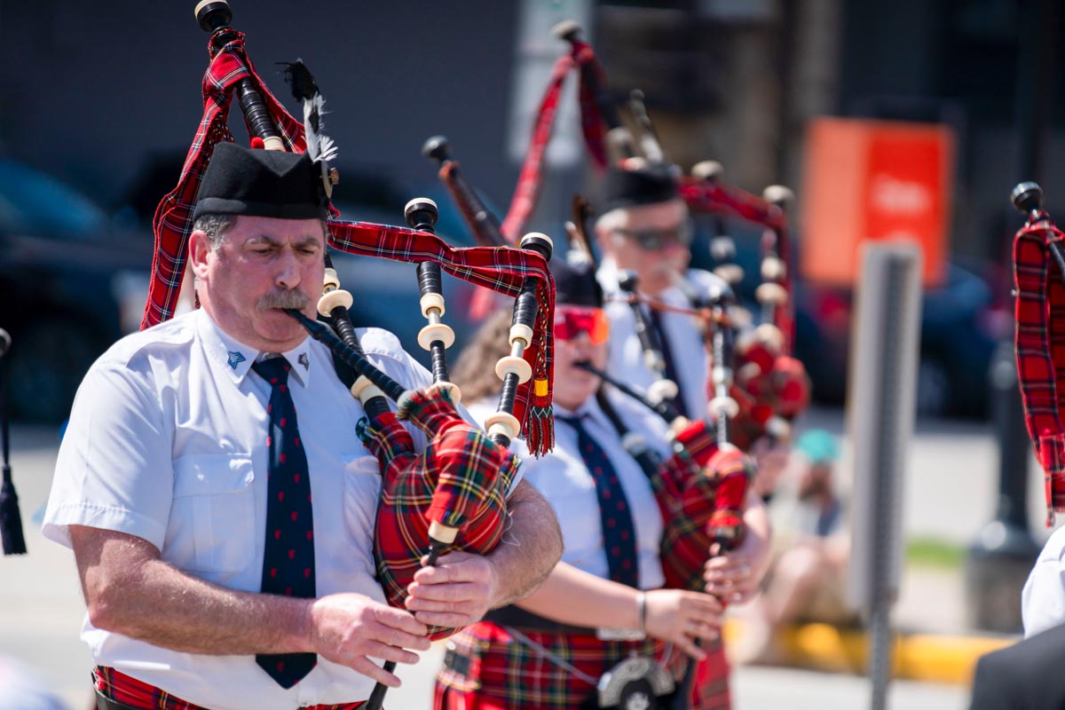SCD Gallery_07 Men and women in white shirts and tartan kilts playing bagpipes outdoors during a parade or event